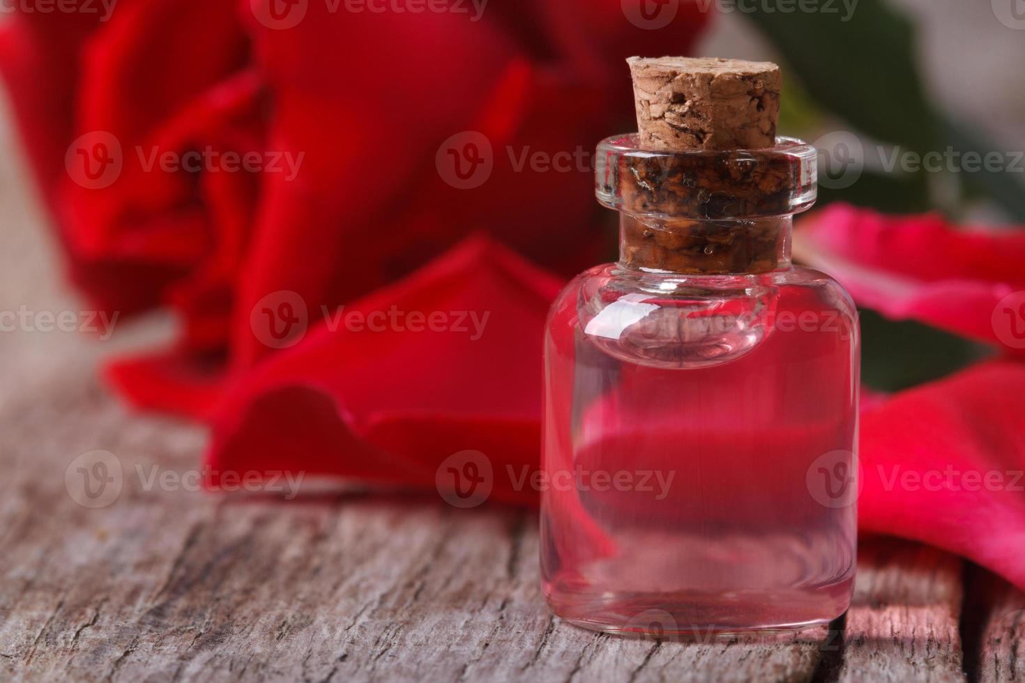 acqua di rose profumata in una bottiglia su un primo piano in legno foto