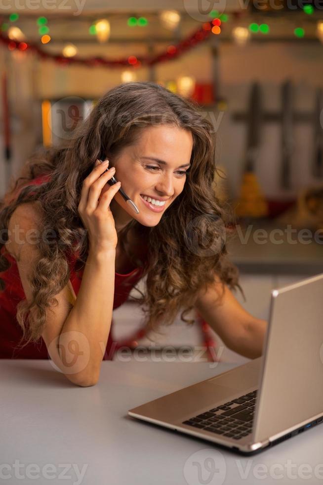 giovane donna felice che ha la chat video sul computer portatile in cucina foto