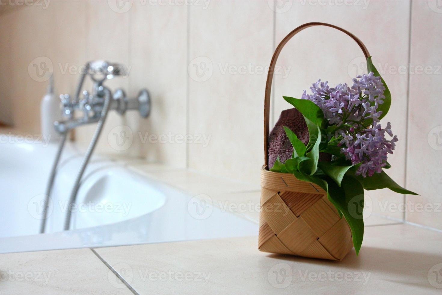 cestino con asciugamano e fiori in bagno foto