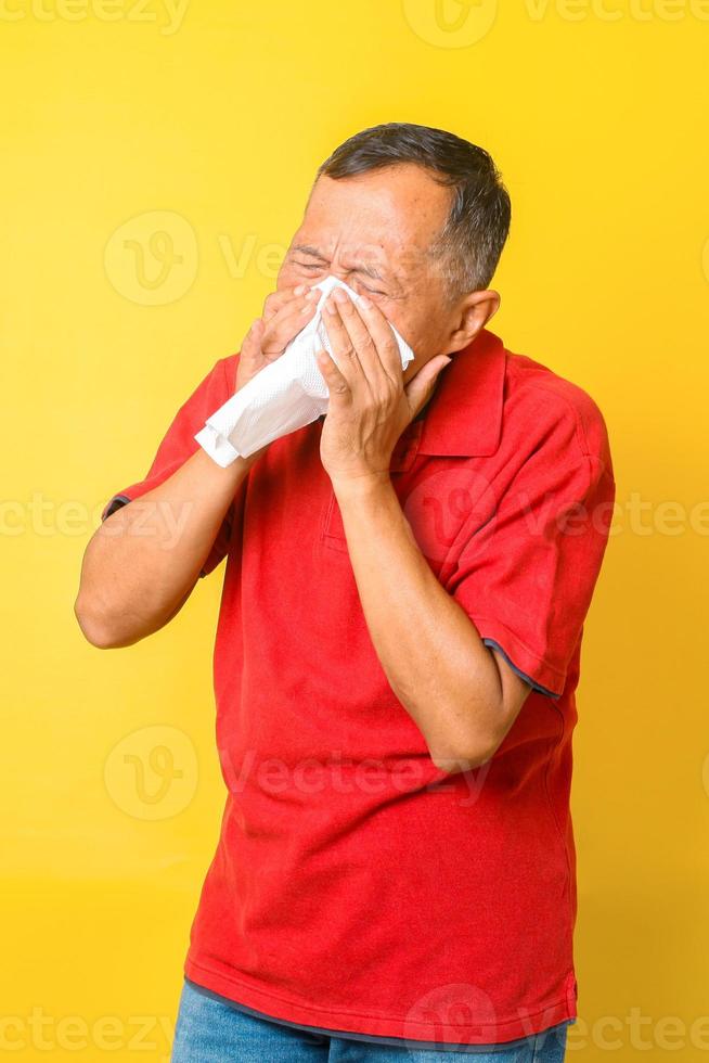 pensionato asiatico che si ammala, ha l'influenza e starnutisce isolati su sfondo giallo. foto