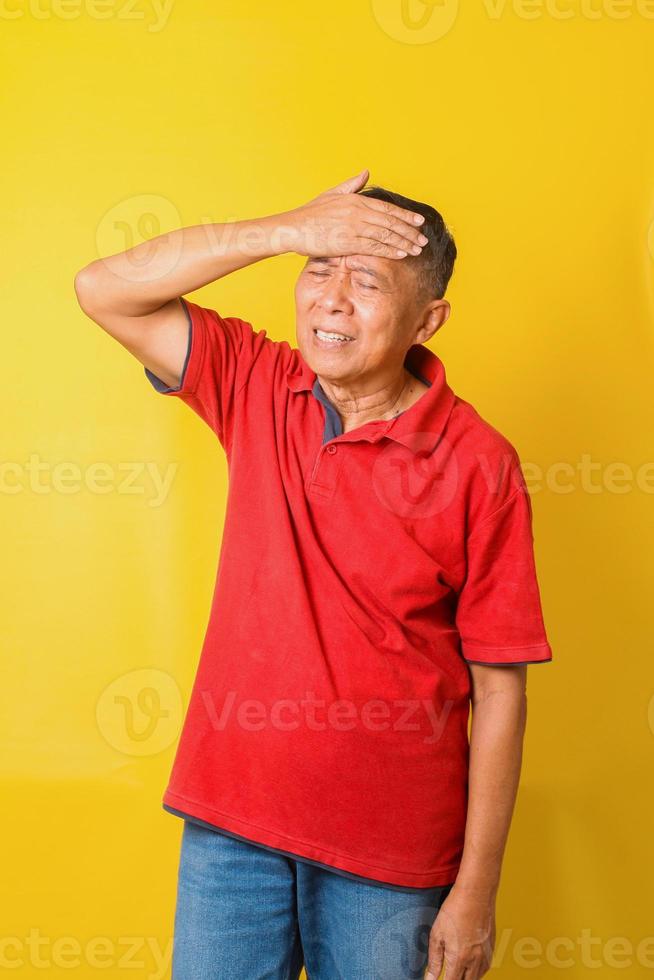 salute, dolore, stress, vecchiaia e concetto di persone - uomo anziano asiatico che soffre di mal di testa isolato su sfondo giallo. foto