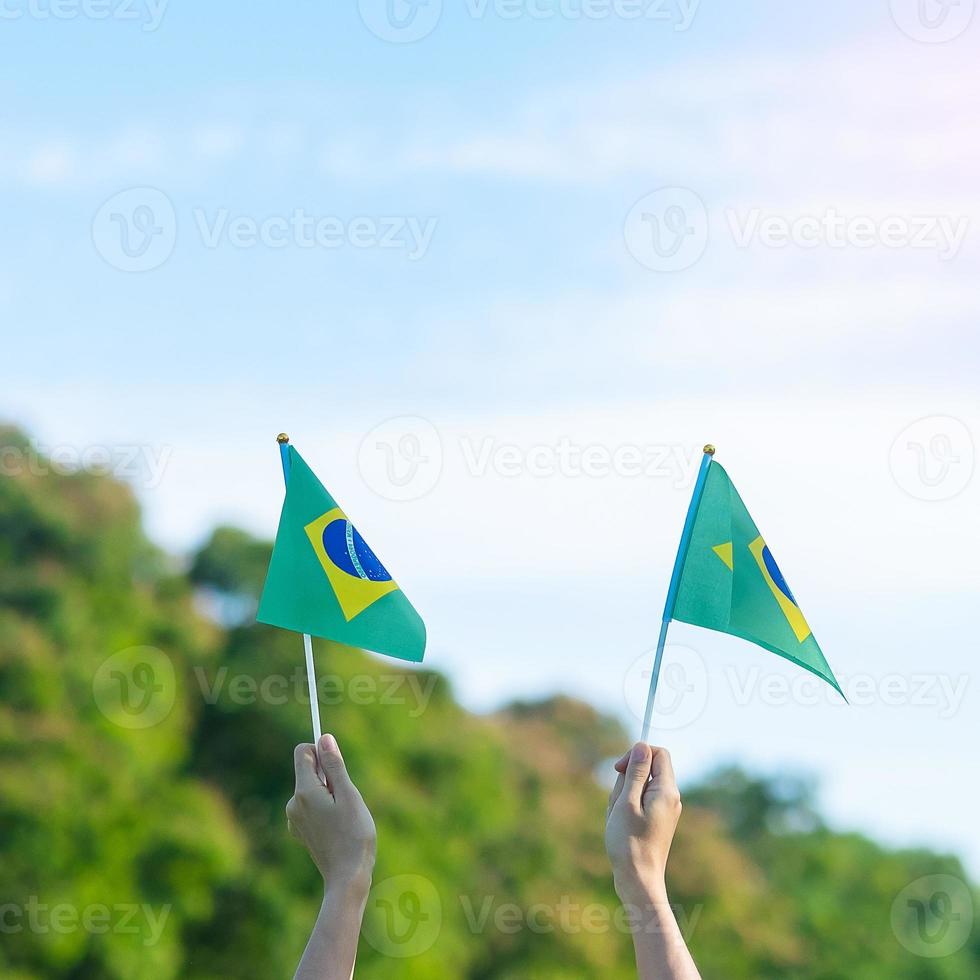 mano che tiene la bandiera del brasile su sfondo blu cielo. festa dell'indipendenza di settembre e concetti di celebrazione felice foto
