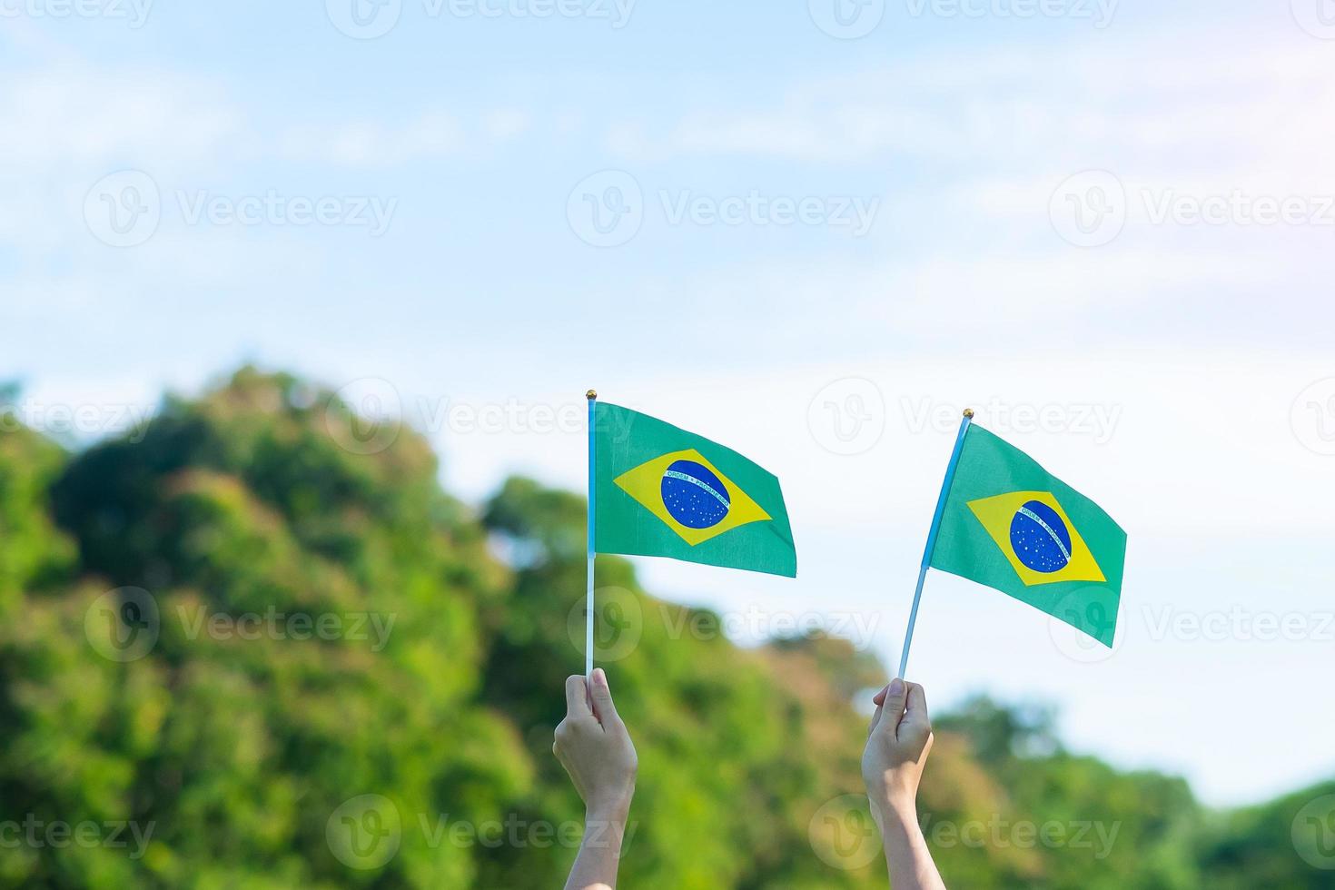 mano che tiene la bandiera del brasile su sfondo blu cielo. festa dell'indipendenza di settembre e concetti di celebrazione felice foto