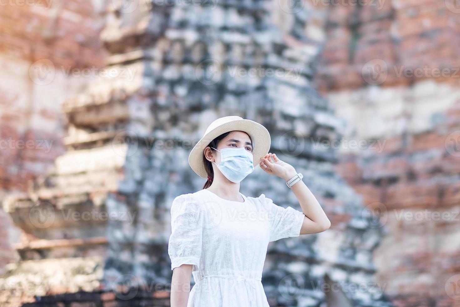 donna turistica in abito bianco che indossa una maschera chirurgica, protezione covid-19 pandemia durante la visita al tempio di wat chaiwatthanaram ad ayutthaya. nuovo concetto di viaggio normale, di sicurezza e di viaggio in Thailandia foto