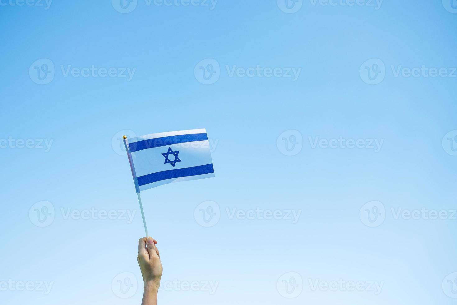 mano che tiene la bandiera israeliana sullo sfondo della natura. giorno dell'indipendenza di israele e concetti di celebrazione felice foto