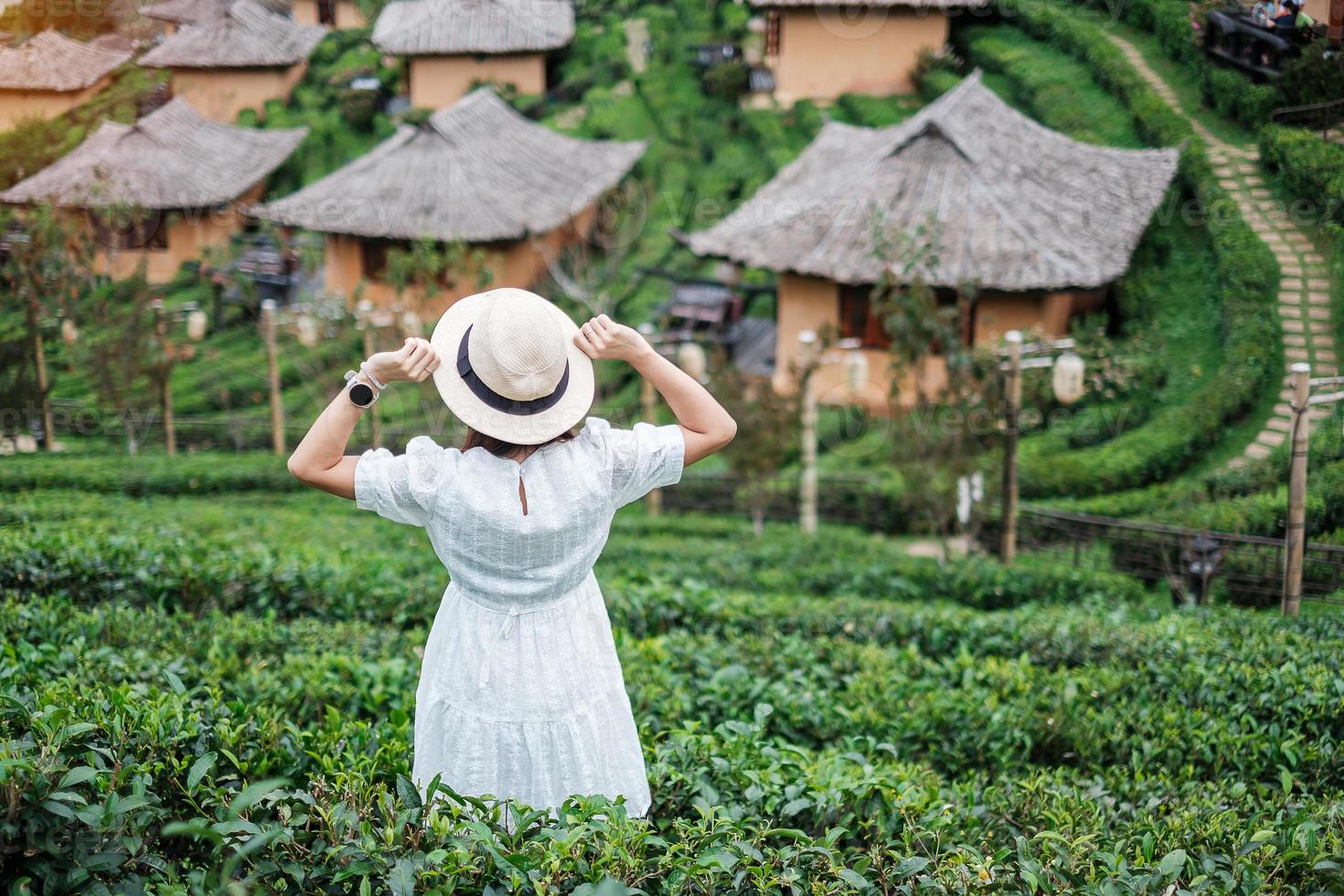 la donna turistica felice in abito bianco gode del bellissimo giardino del tè. viaggiatore che visita nel villaggio thailandese di ban rak, figlio di mae hong, tailandia. concetto di viaggio, vacanza e vacanza foto