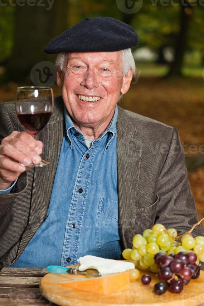 uomo francese che gode del vino rosso e del formaggio nella foresta di autunno. foto