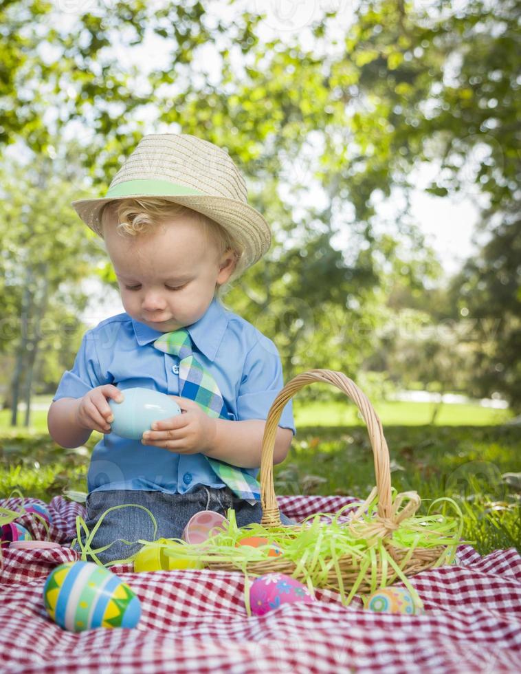ragazzino sveglio che gode delle sue uova di Pasqua fuori nel parco foto
