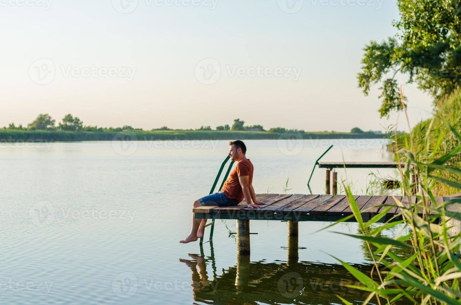 giovane uomo seduto rilassante e godersi la vista dal molo foto