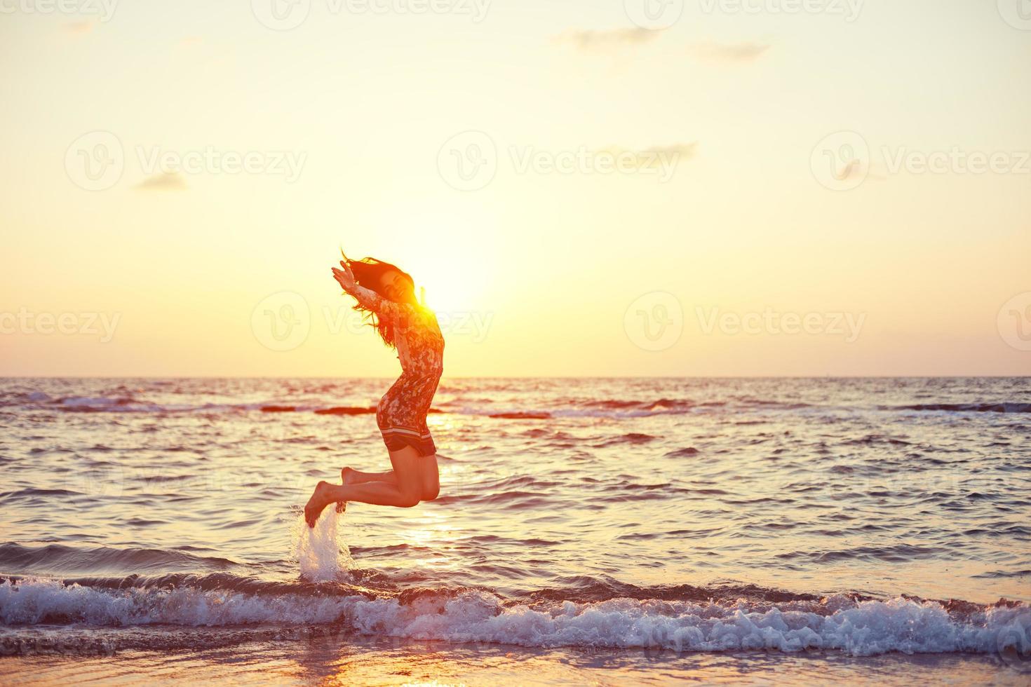 bella ragazza che salta nell'oceano foto