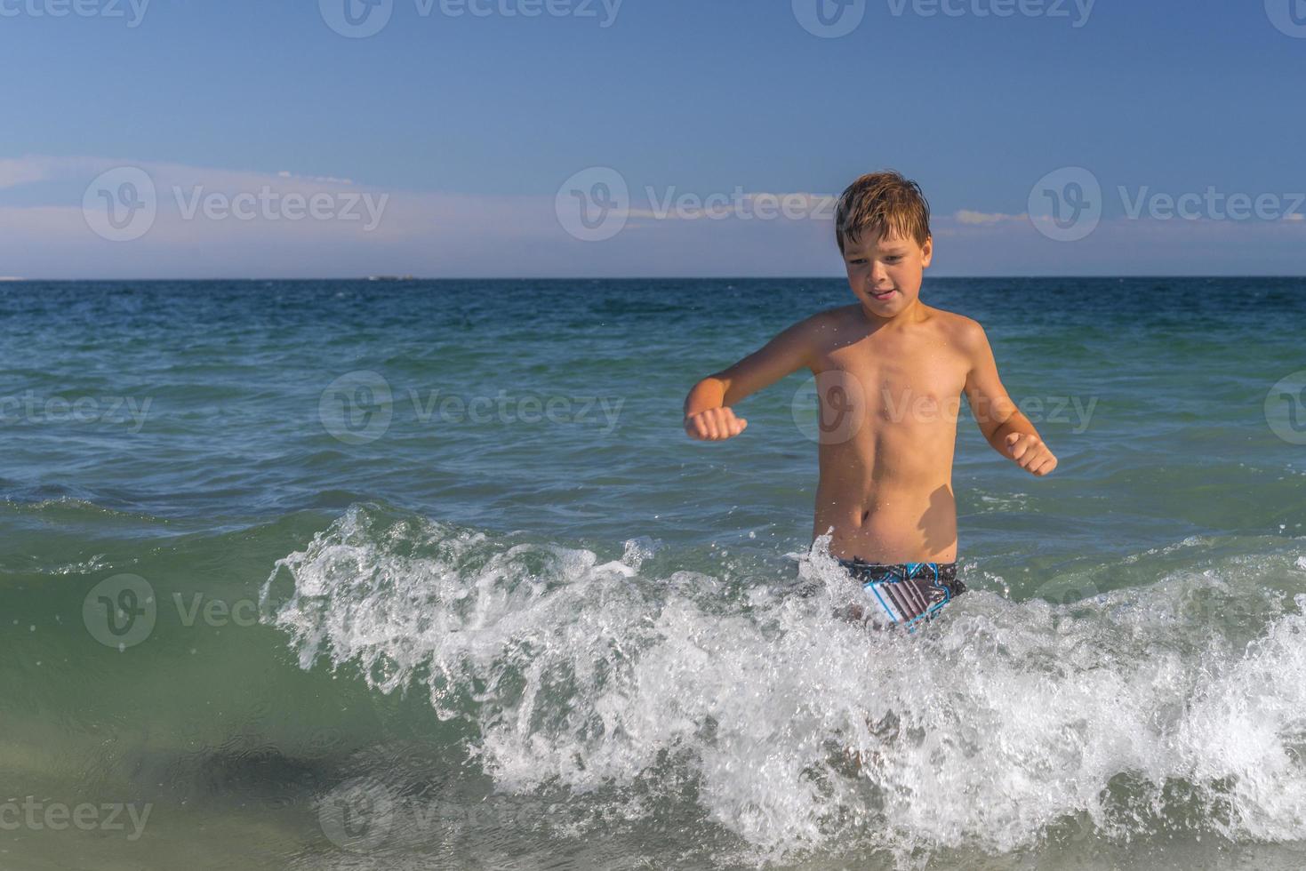 ragazzo che corre attraverso le onde in spiaggia foto