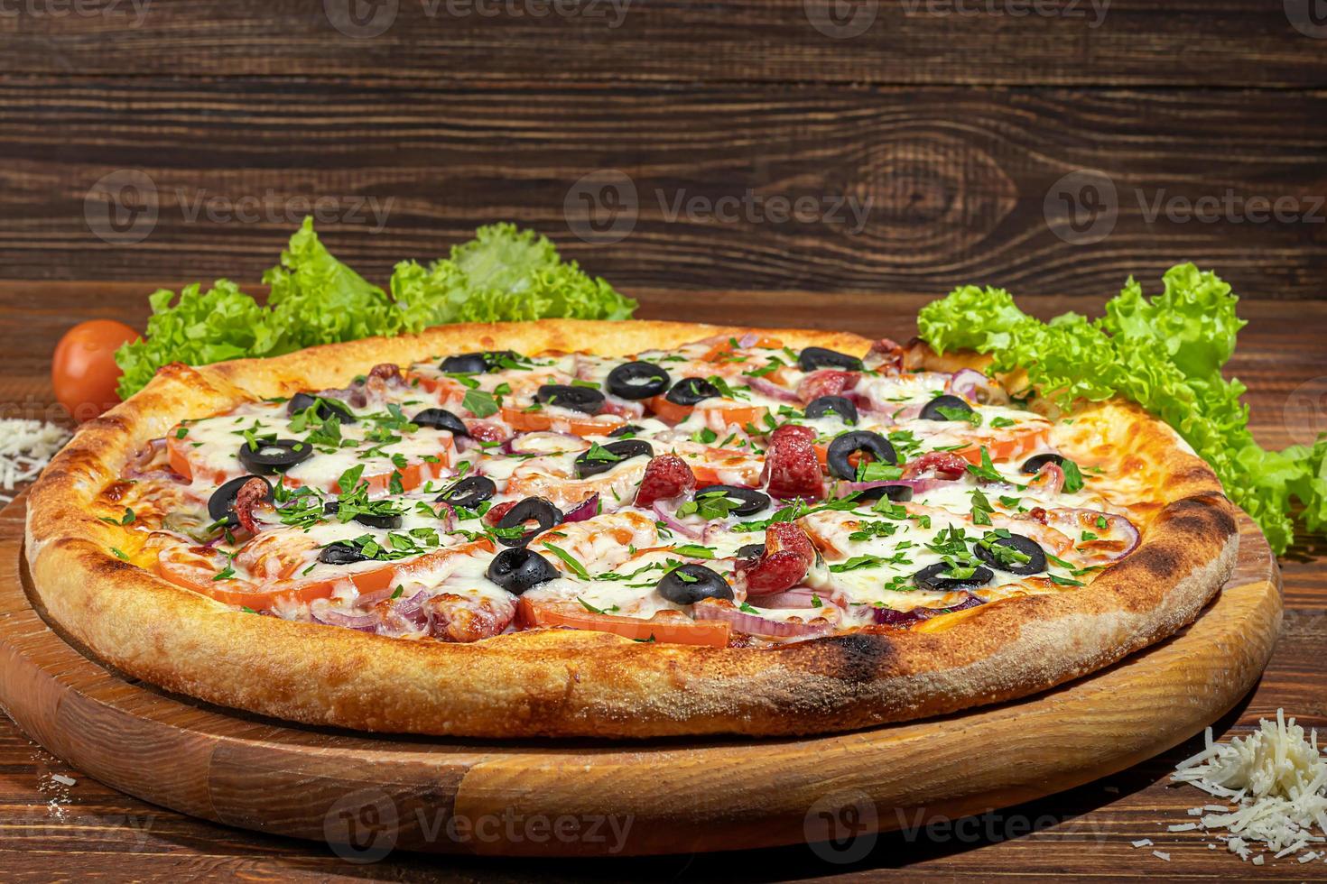 pizza con pancetta e formaggio, erbe aromatiche e pomodorini. con mozzarella, gamberi e polpi, cozze e altri prodotti su fondo di legno. foto