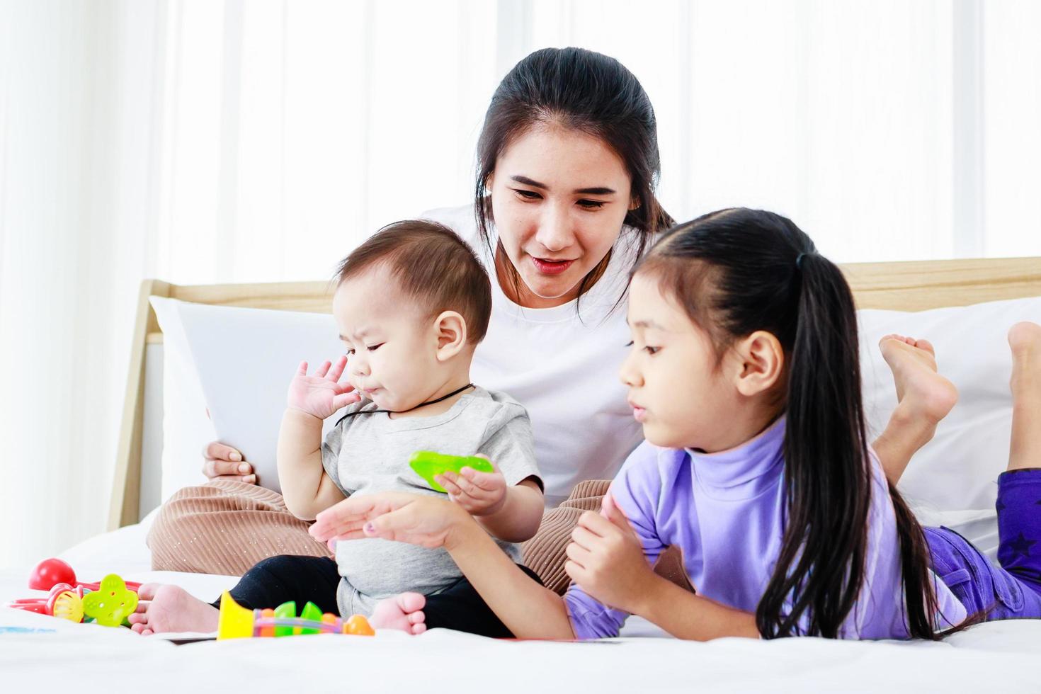 donna impegnata che lavora da casa e si prende cura del suo bambino e della sua piccola figlia foto