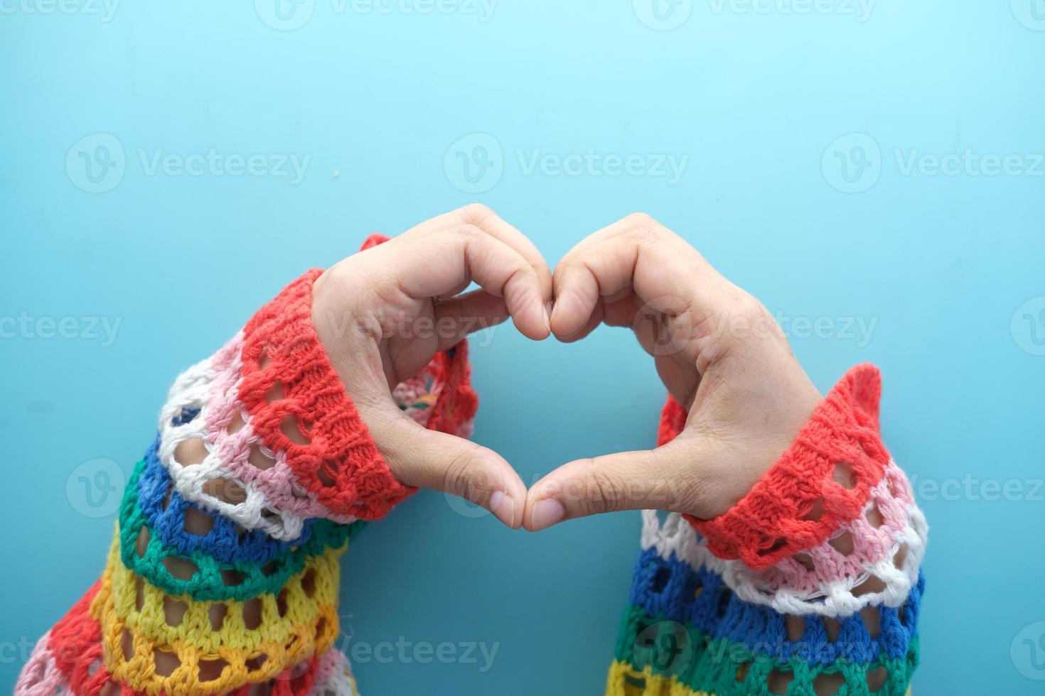 mani femminili che fanno il cuore del segno su sfondo colorato foto