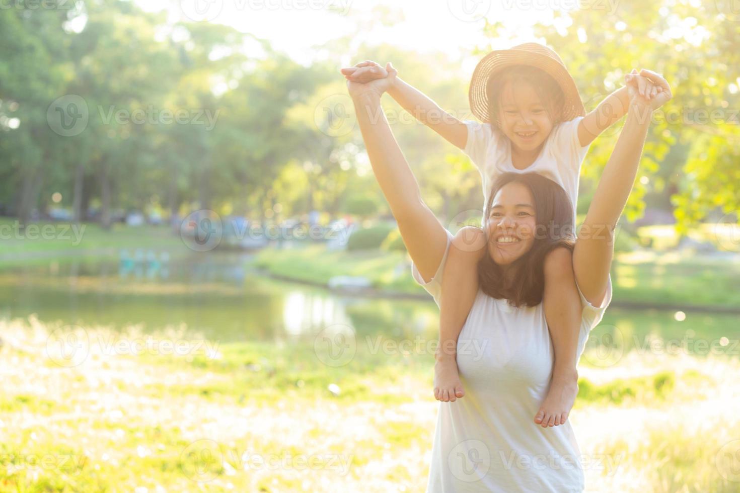 bella giovane madre asiatica che porta la piccola figlia con il sorriso, il bambino cavalca il collo della mamma con felicità e allegri insieme nel parco, famiglia di stile di vita con concetto di divertimento e divertimento. foto