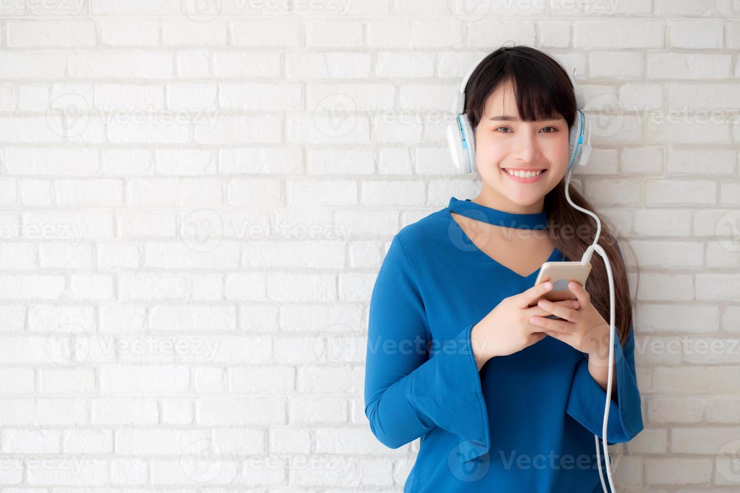 bello ritratto asiatico giovane donna in piedi felice divertirsi e divertirsi ascolta musica con le cuffie su cemento cemento sfondo, stile di vita della ragazza rilassarsi radio sonora con auricolare, concetto di tecnologia. foto