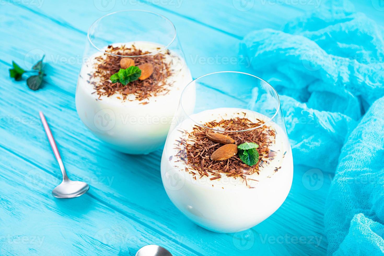 budino di latte dolce con mandorle e gocce di cioccolato su sfondo blu foto