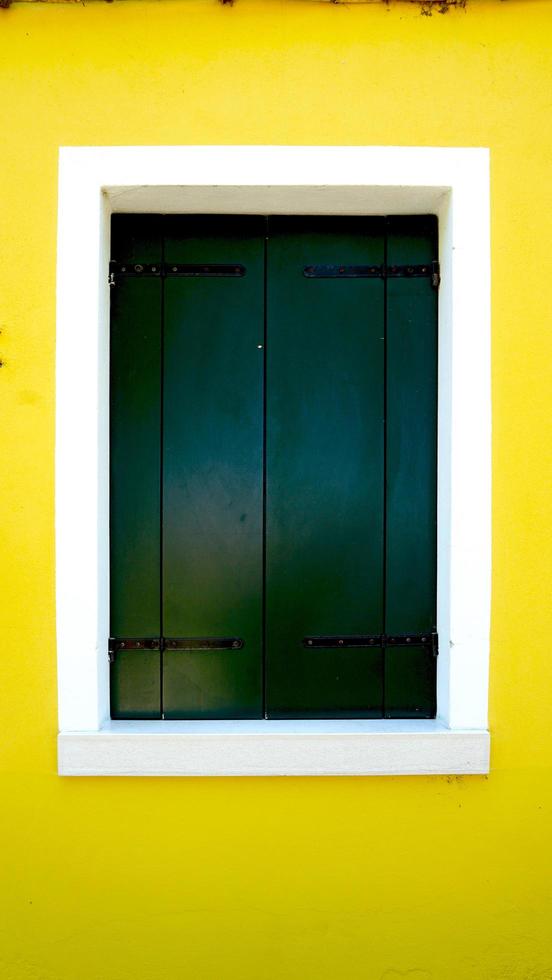 finestra in legno verde a burano con parete giallo brillante foto