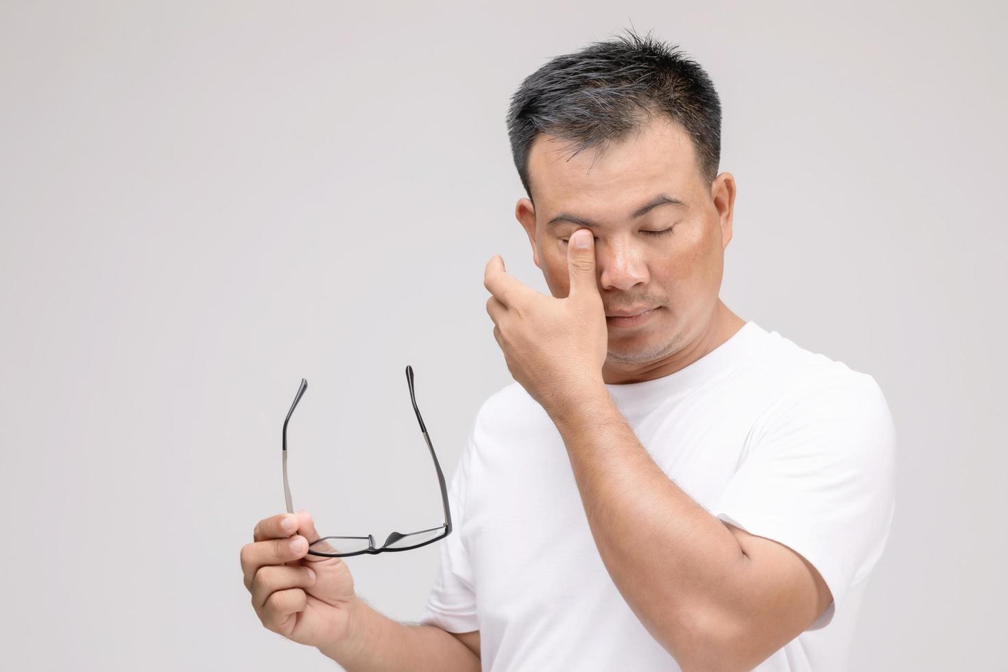 concetto di irritazione agli occhi, ritratto di un uomo asiatico in postura di occhi stanchi, irritazione o problemi agli occhi. girato in studio isolato su grigio foto