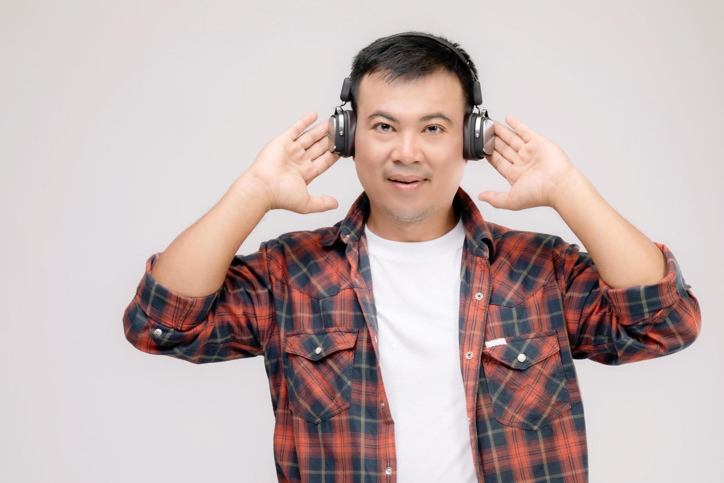 ritratto uomo asiatico che ascolta la canzone o la musica dalle cuffie nere. girato in studio isolato su grigio foto