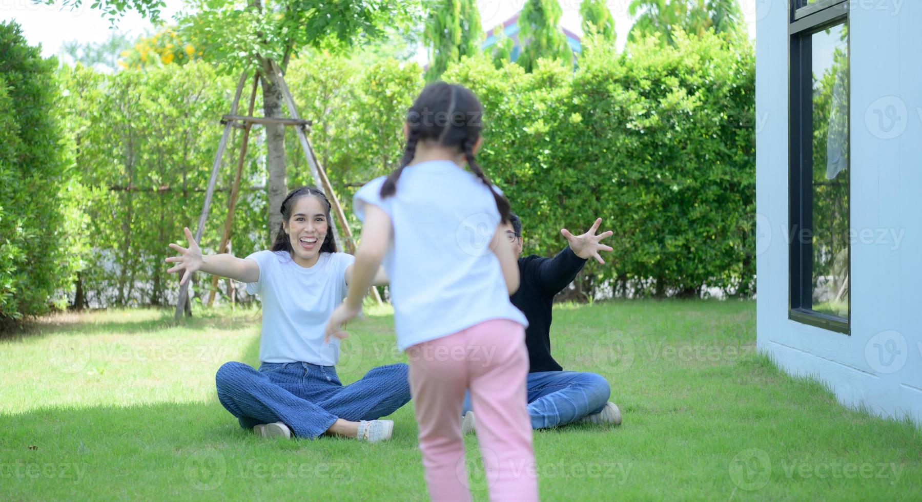 famiglia asiatica con padre, madre e figlia che si divertono felicemente nel giardino di casa foto