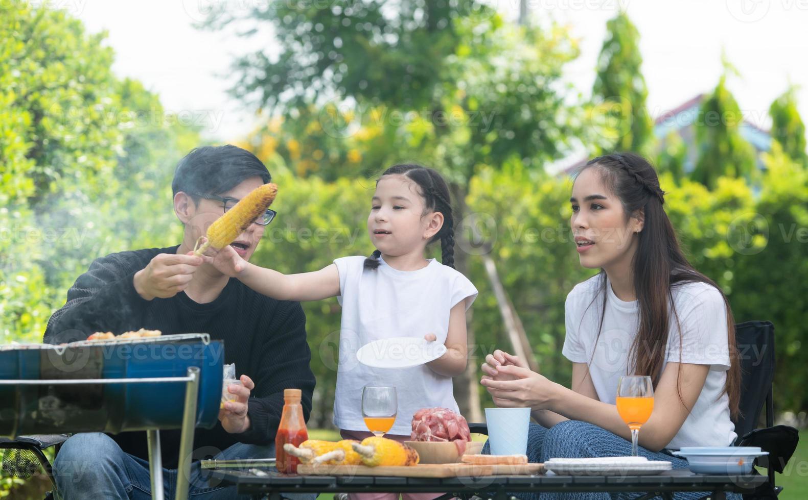 le attività per le vacanze in famiglia includono padre, madre e figli con barbecue da campeggio e giocare in cortile insieme felicemente in vacanza. foto