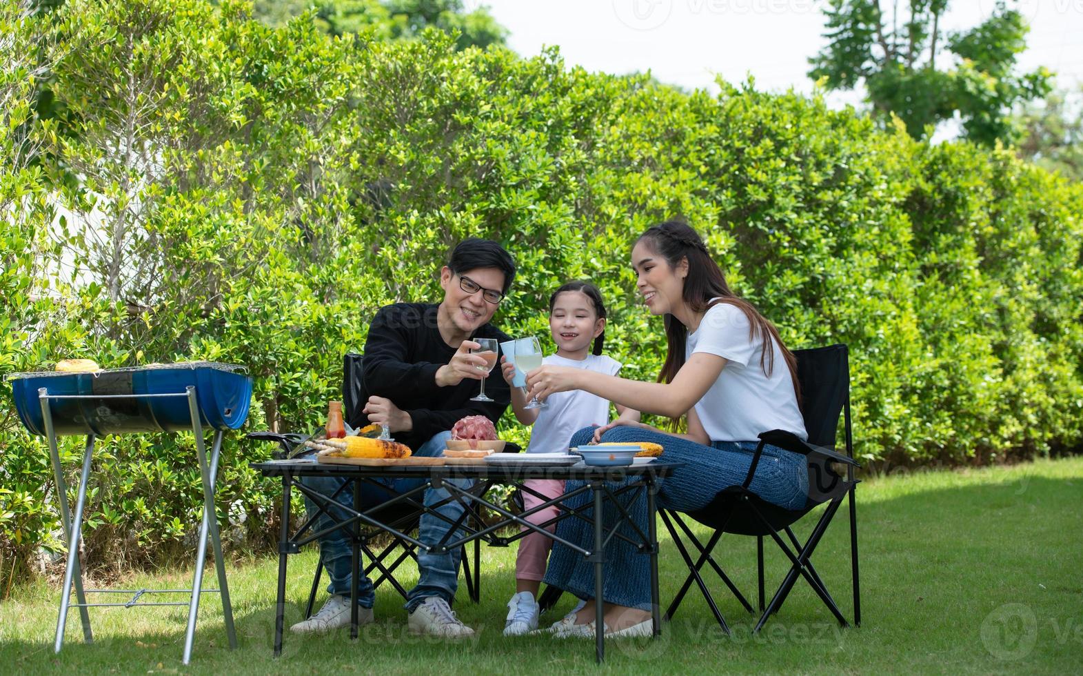le attività per le vacanze in famiglia includono padre, madre e figli con barbecue da campeggio e giocare in cortile insieme felicemente in vacanza. foto