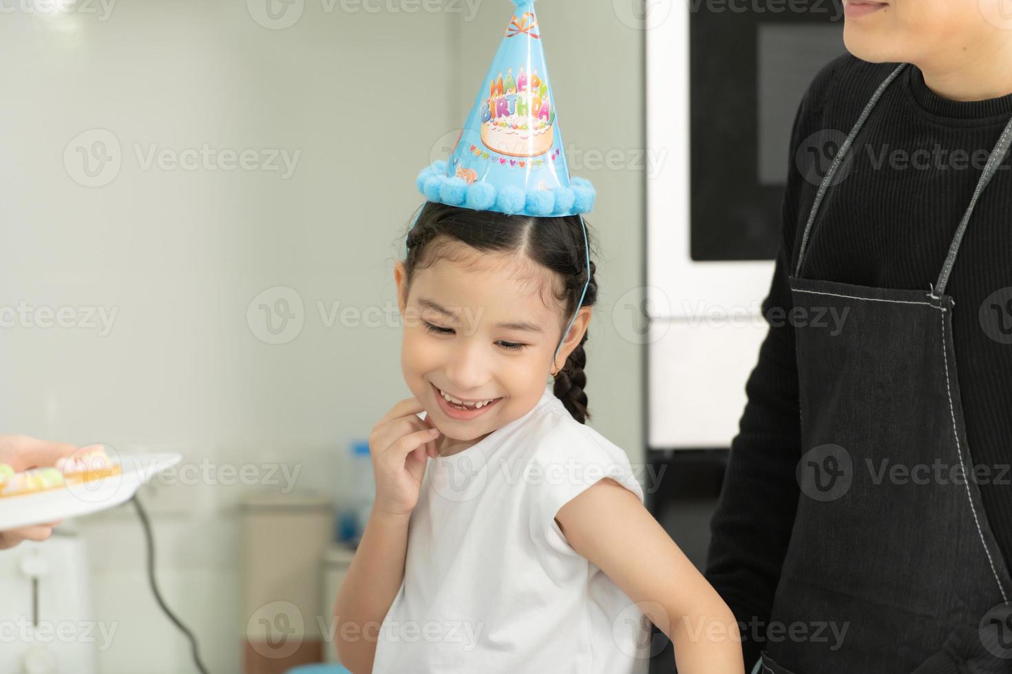 la famiglia asiatica di nuova generazione cucina insieme e organizza una piccola festa di compleanno per la nostra piccola figlia nella cucina di casa foto