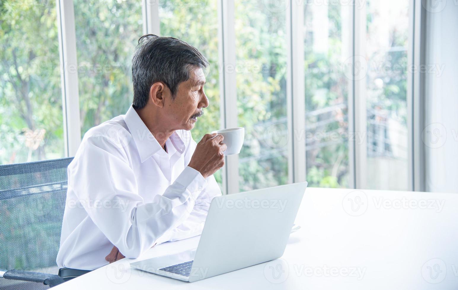 uomo d'affari asiatico con camicia bianca che lavora e beve caffè nella sala riunioni dell'ufficio foto