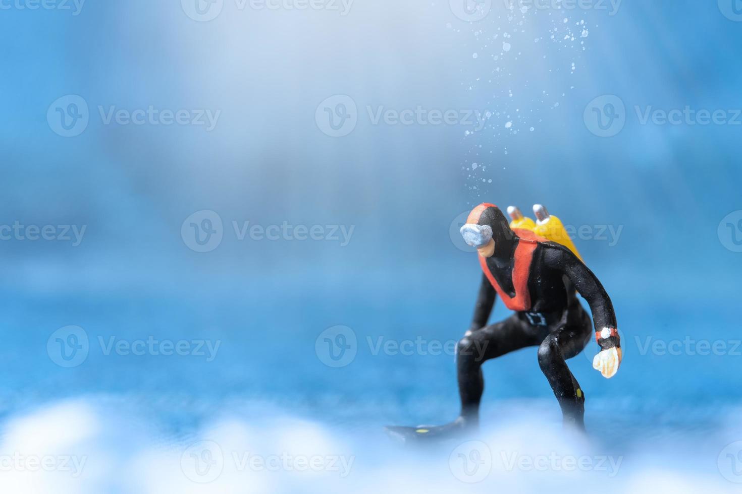 persone in miniatura subacqueo in piedi sott'acqua con sfondo blu foto
