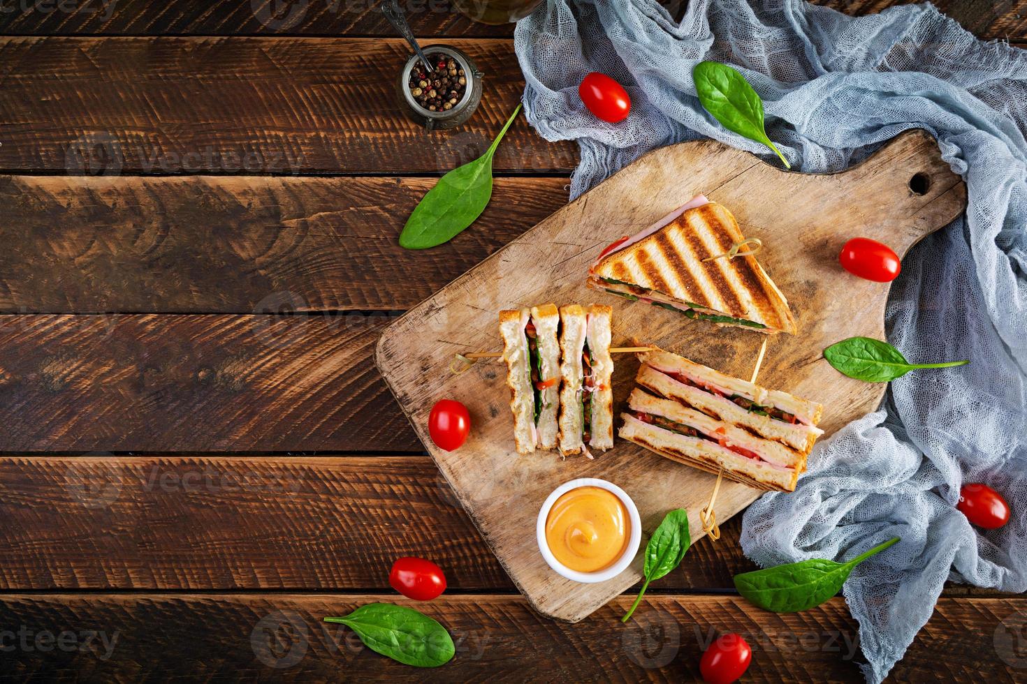 club sandwich con prosciutto, pomodoro, formaggio e spinaci. panini alla griglia. vista dall'alto foto