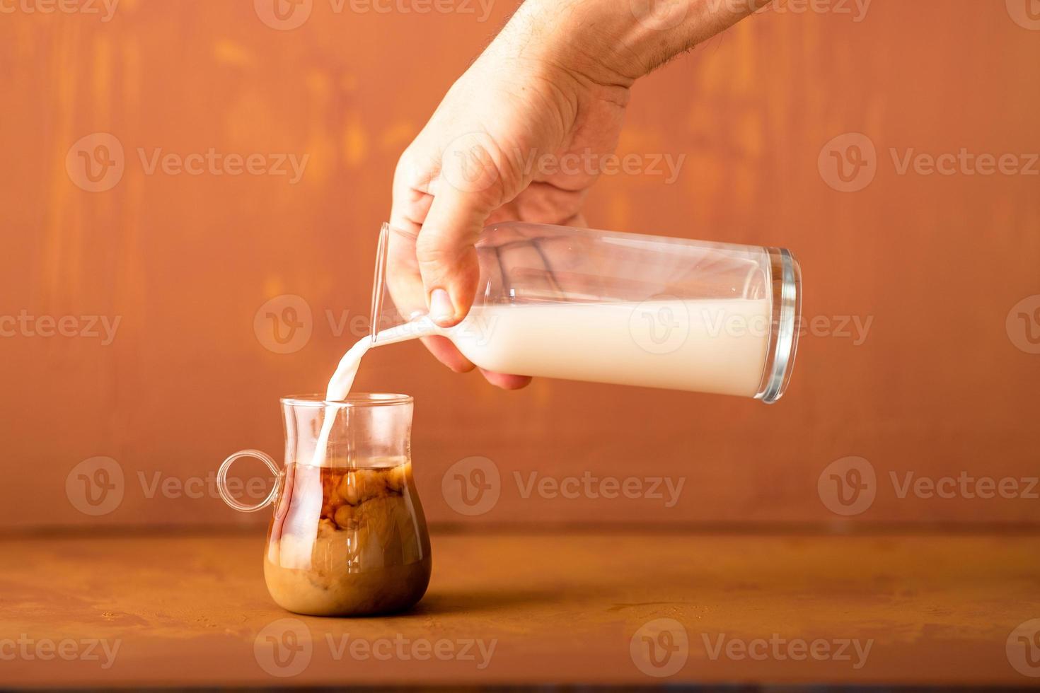 la mano sta versando il latte al caffè preparato in studio con spazio per la copia. foto