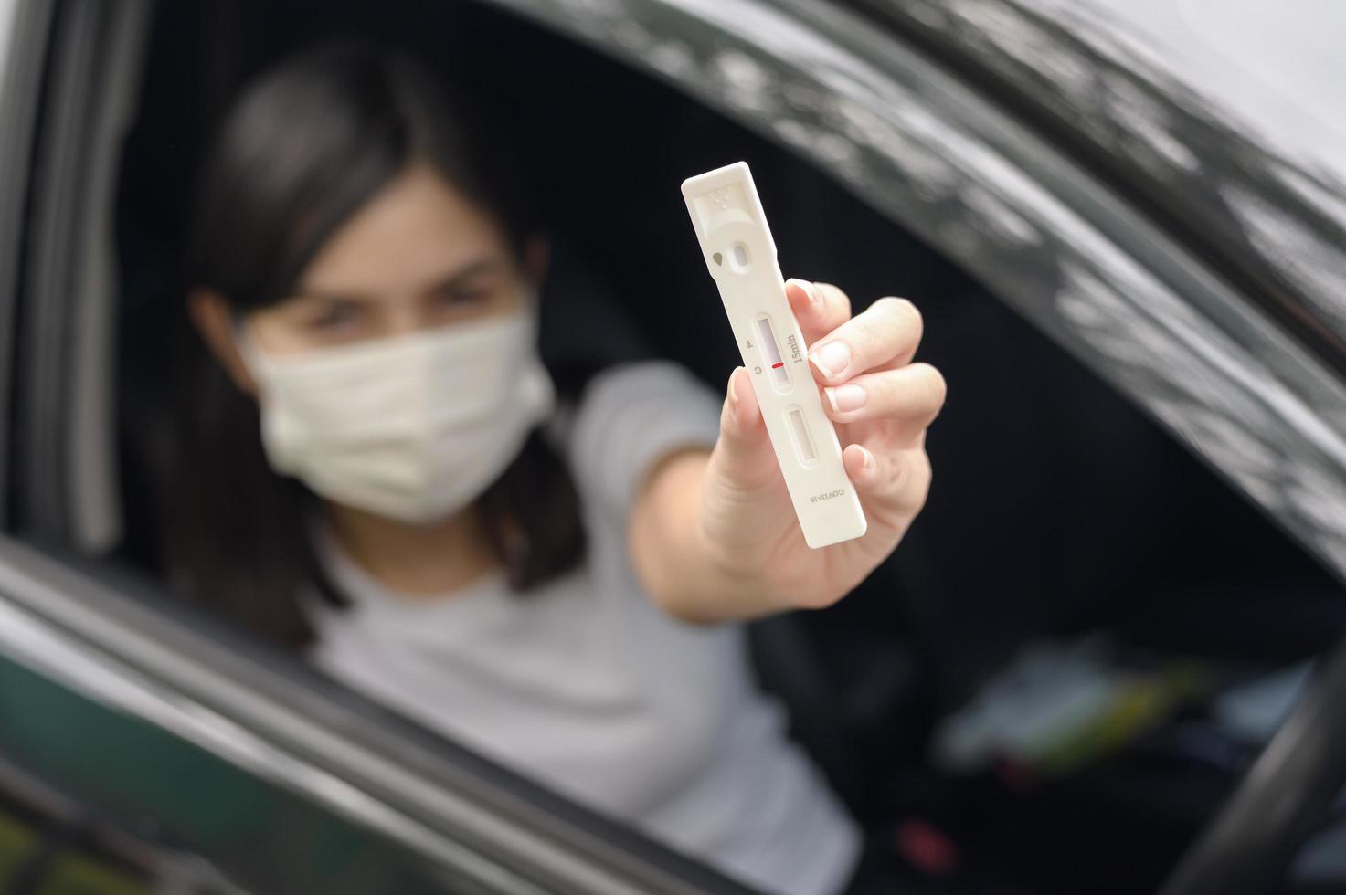 una donna che tiene in macchina, fa un test di auto-raccolta per un test covid-19, salute e sicurezza foto