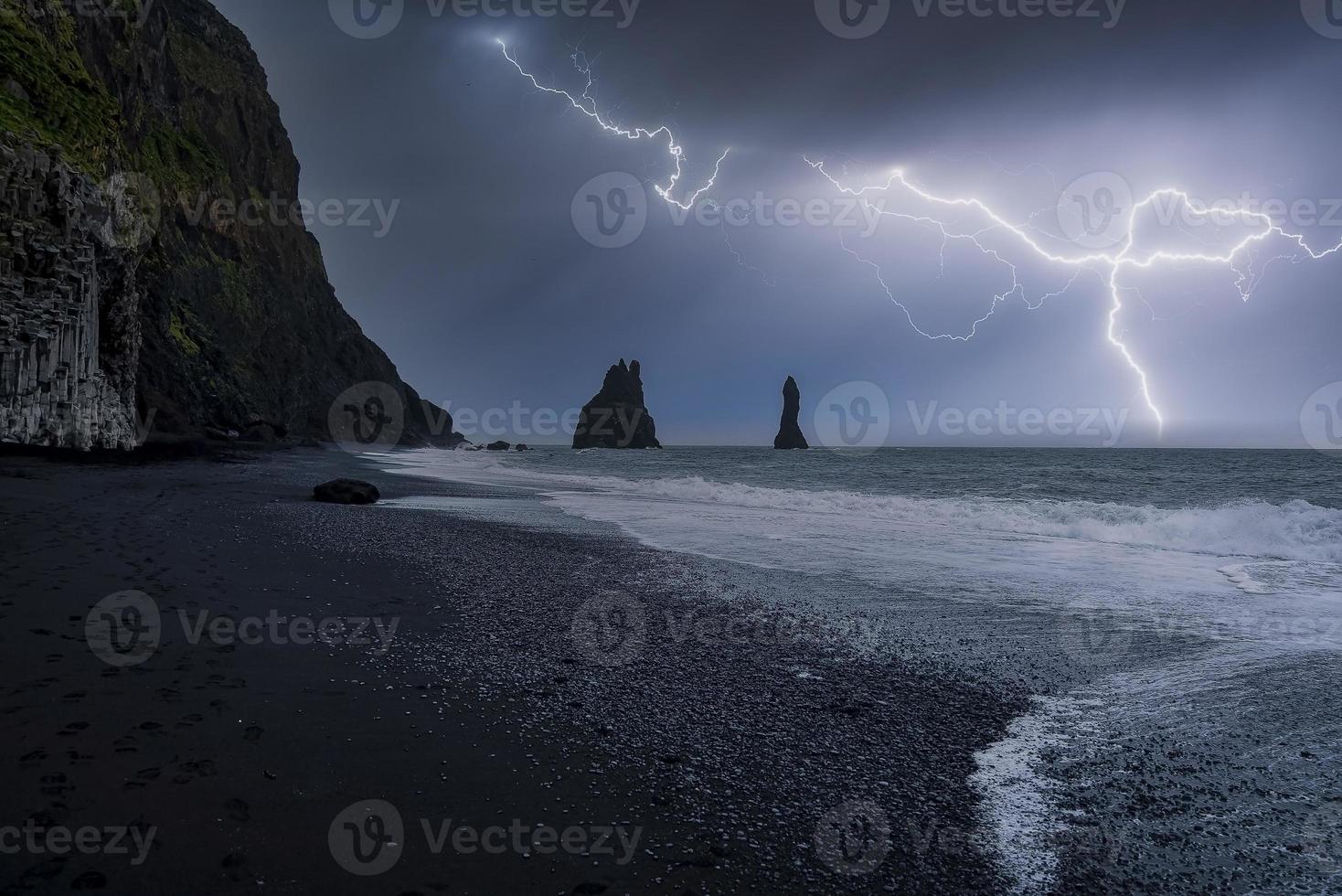 vista idilliaca del fulmine sulla spiaggia nera di reynisfjara contro la notte tempestosa foto