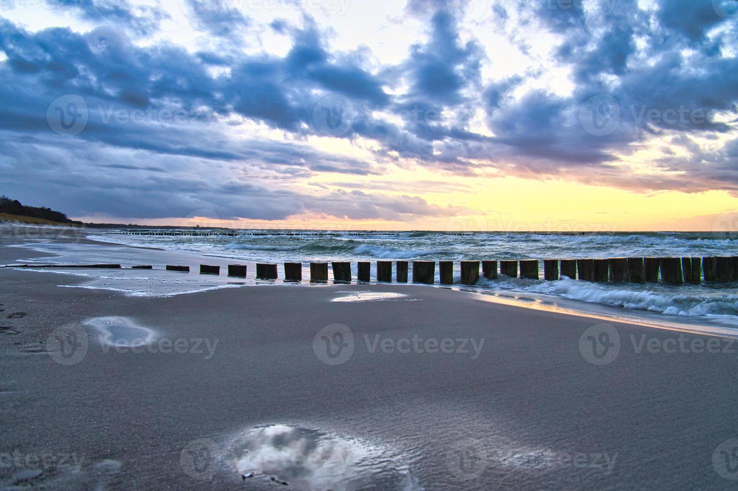 tramonto sulla spiaggia del mar baltico. riflessione sulla spiaggia. i pennelli raggiungono il mare. foto