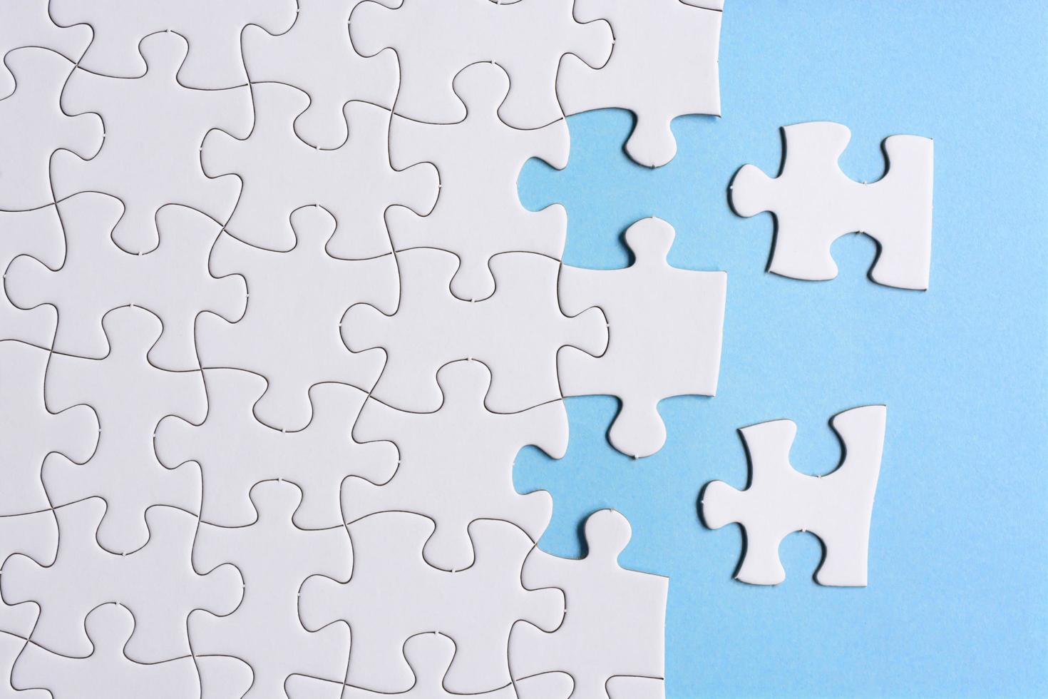 puzzle bianco con alcuni pezzi mancanti su sfondo blu. copia spazio. foto