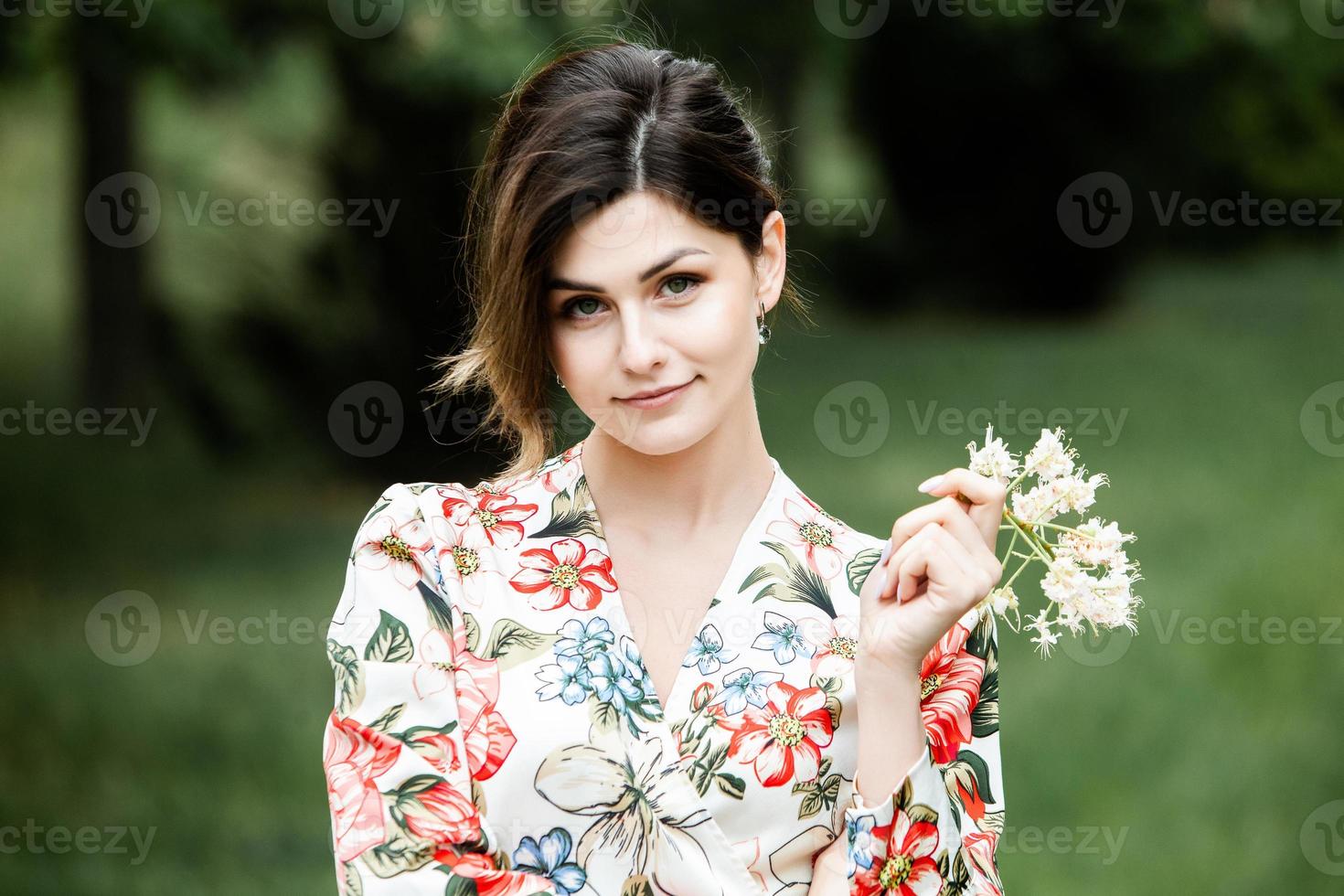 ritratto di donna con i capelli mossi dal vento. ritratto di giovane bella ragazza bruna russa al parco verde estivo. donna bianca europea in abito. foto