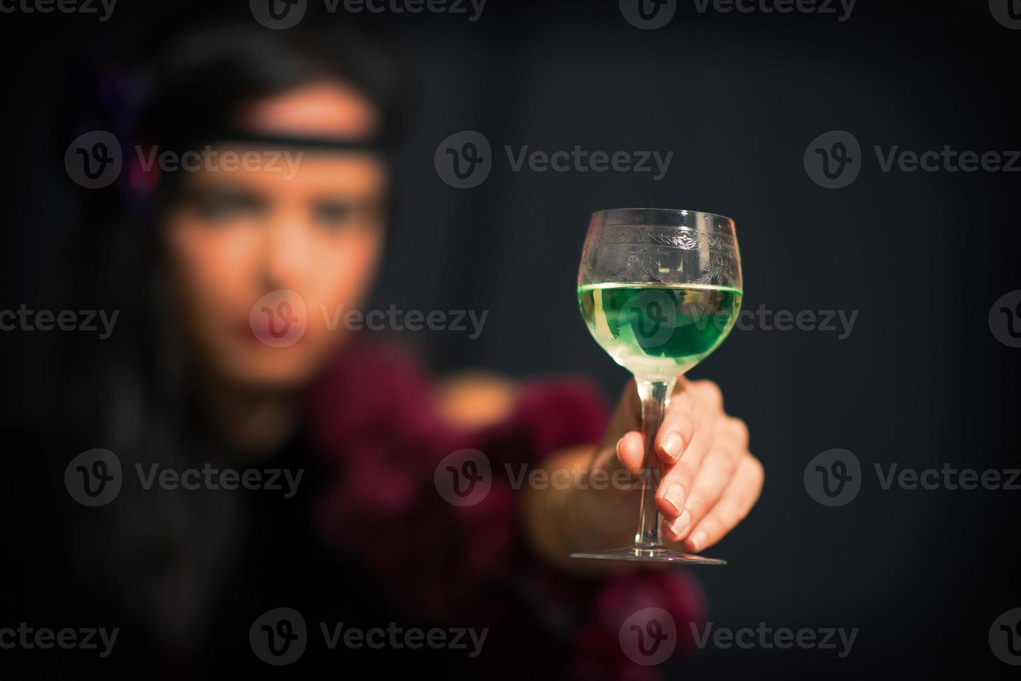 bicchiere con assenzio. tiene una mano con una donna sfocata foto