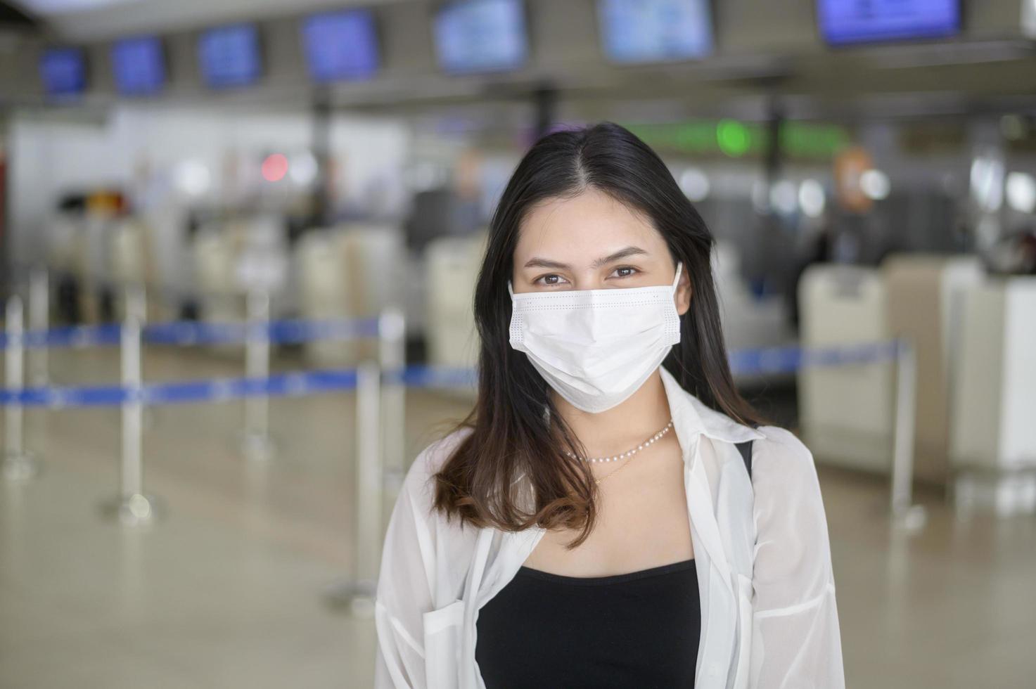 una donna viaggiatrice indossa una maschera protettiva nell'aeroporto internazionale, viaggia sotto la pandemia covid-19, viaggi di sicurezza, protocollo di allontanamento sociale, nuovo concetto di viaggio normale. foto