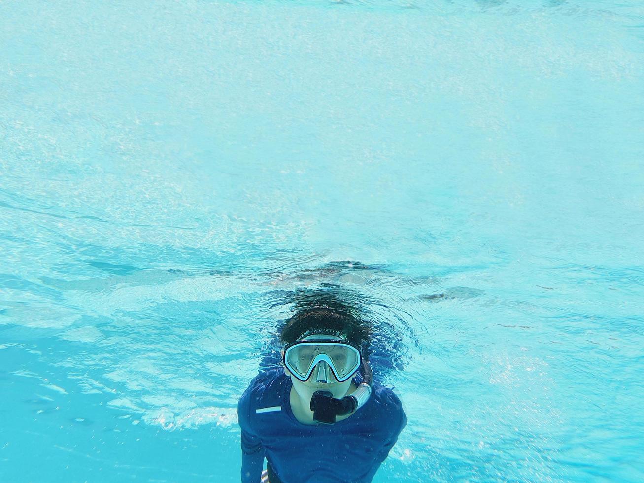 il ragazzo si sta tuffando usando la presa d'aria nell'acqua limpida e pulita del mare foto