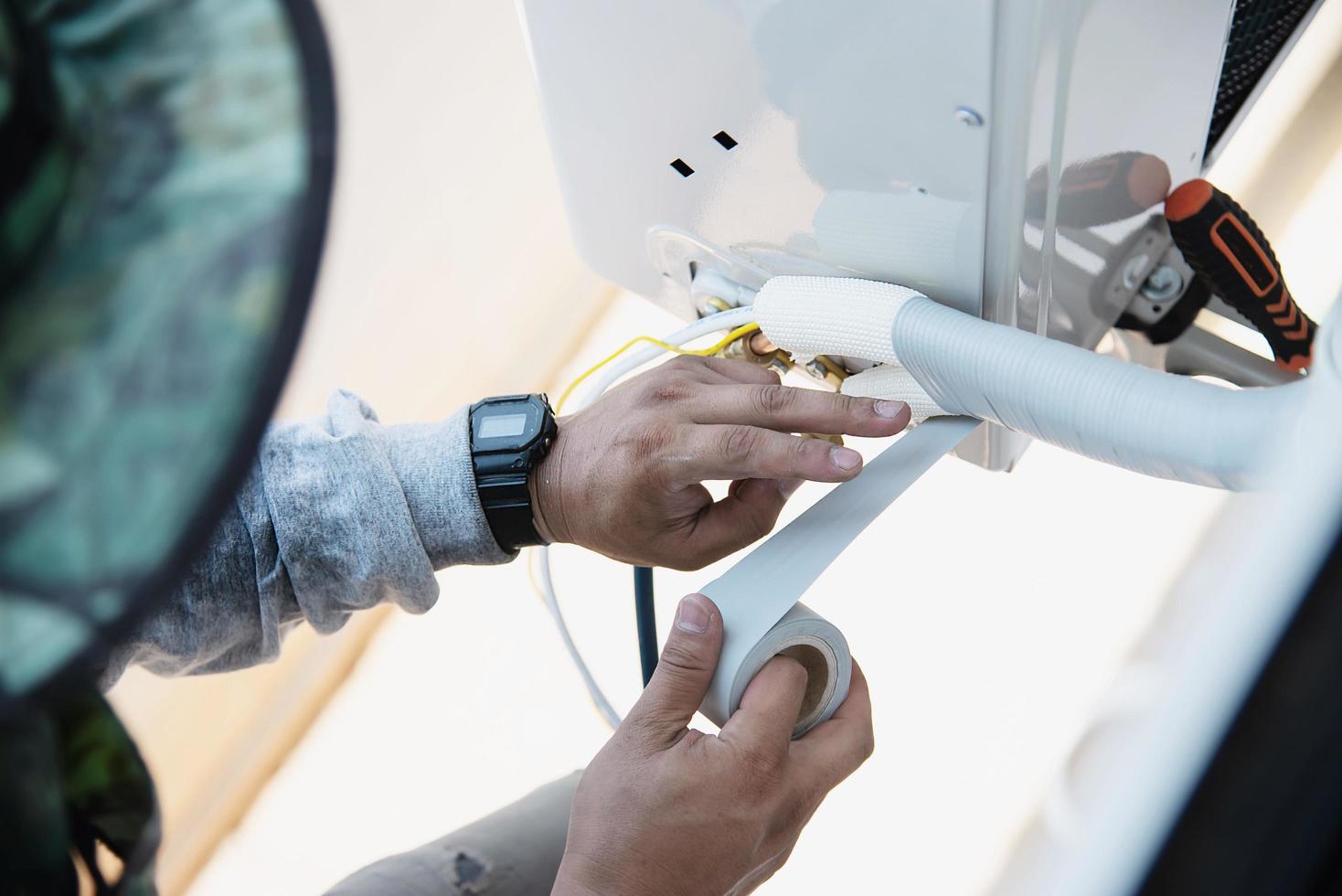 l'uomo sta installando il compressore a parete del condizionatore d'aria durante la stagione calda foto