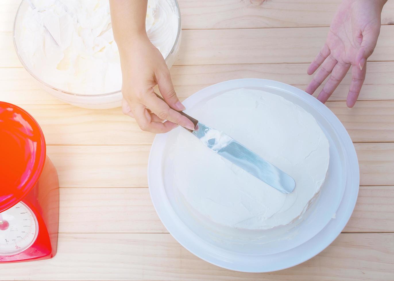 mettendo la torta alla crema di burro a mano usando la spatola foto