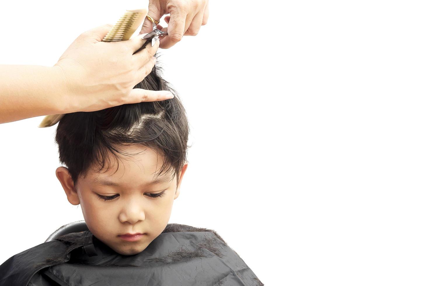 un ragazzo è tagliato i capelli dal parrucchiere isolato su sfondo bianco foto
