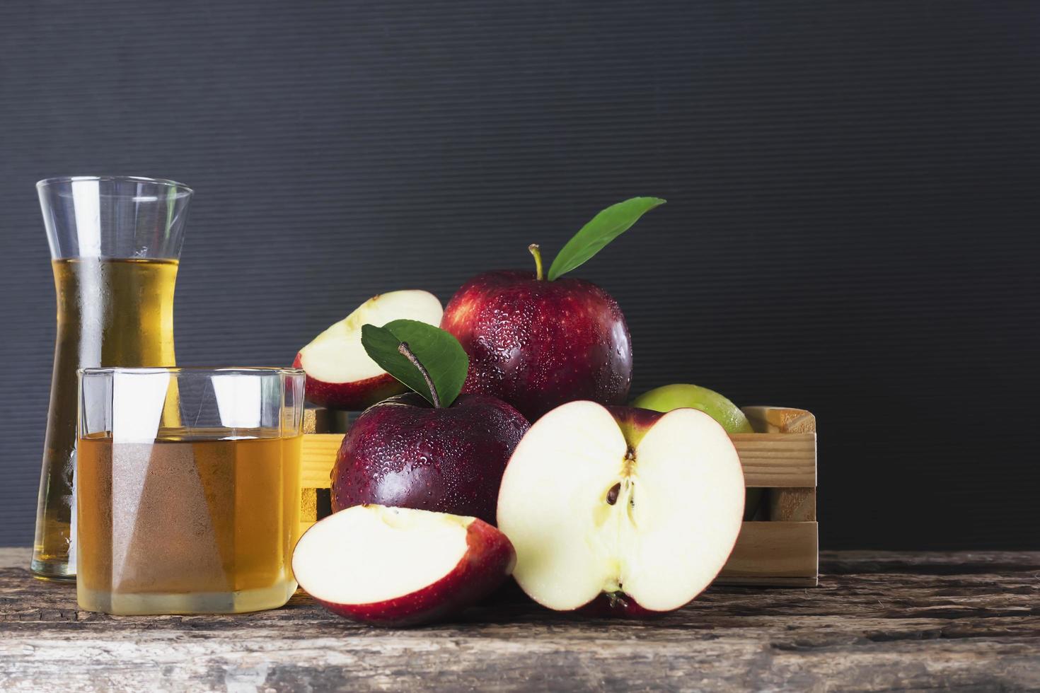 mela fresca in scatola di legno con succo di mela su sfondo nero - frutta fresca e succo di frutta concetto di sfondo foto