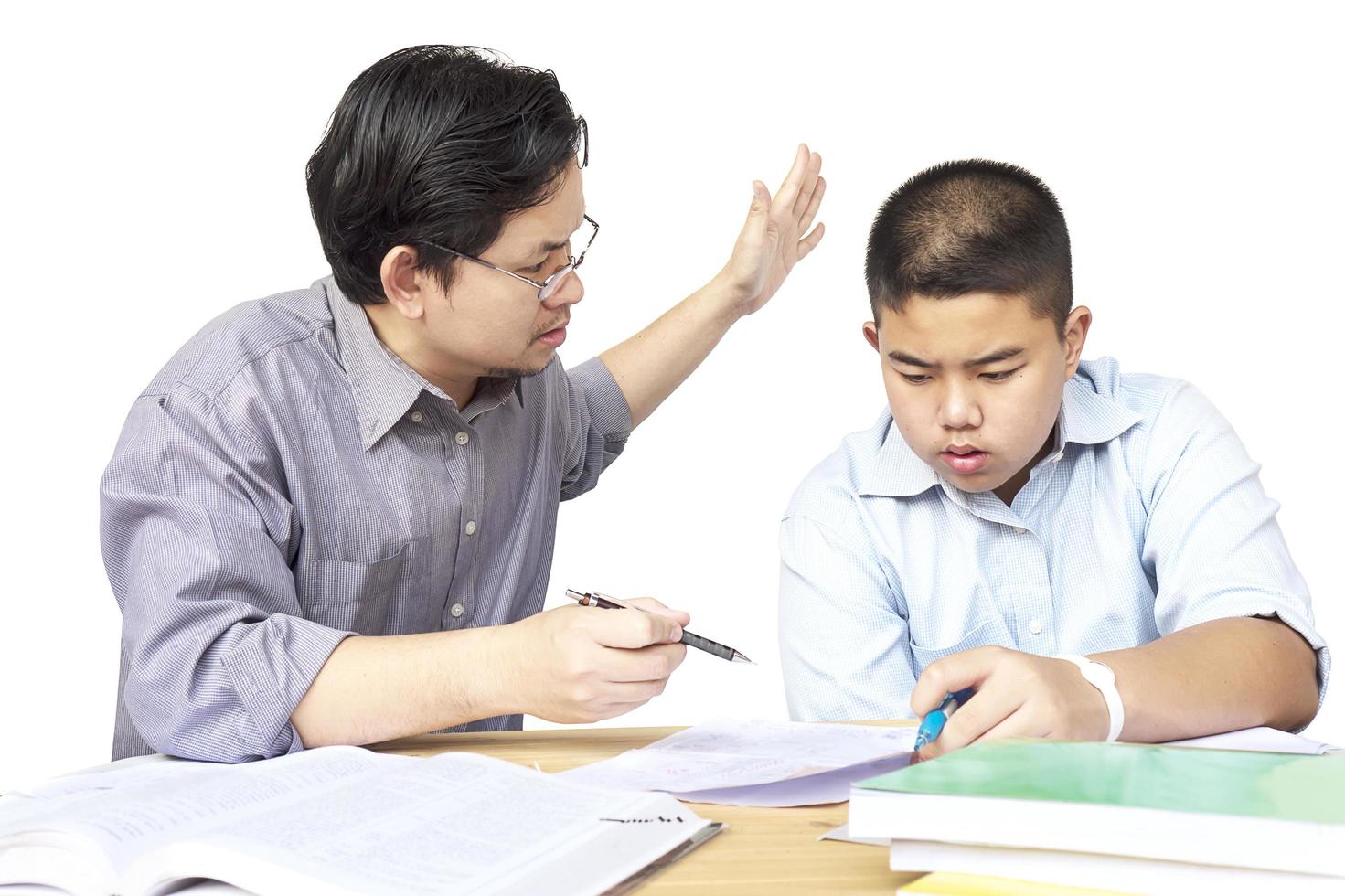 padre asiatico che insegna seriamente i compiti a suo figlio di 14 anni foto