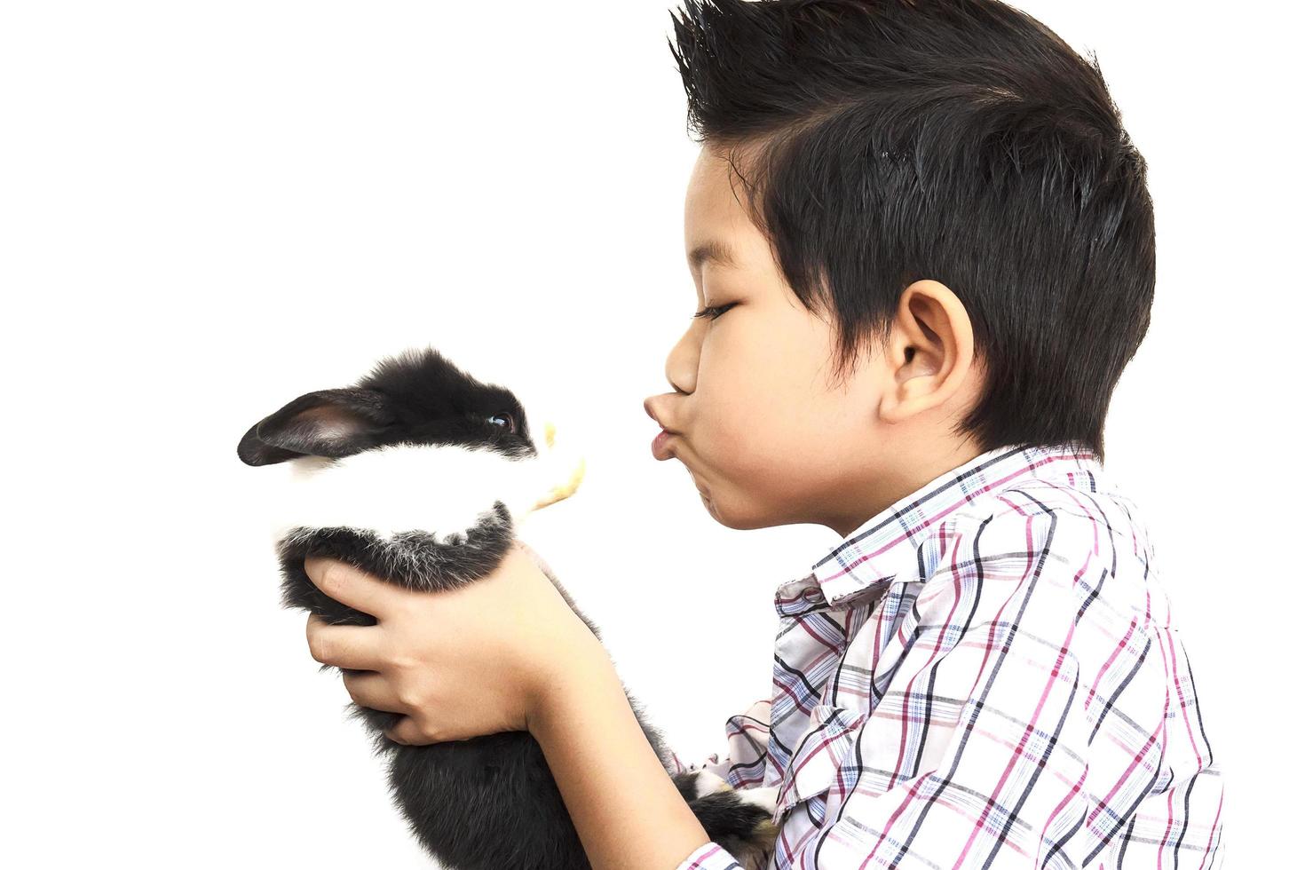 bambino asiatico che gioca con il coniglio adorabile del bambino isolato sopra bianco foto