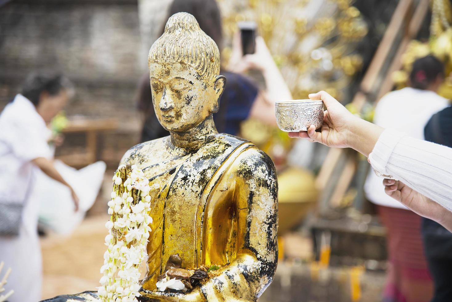 persone che versano acqua su un'immagine di buddha questo è un gesto di adorazione - le persone partecipano al festival bhudista tradizionale annuale di chiang mai locale. foto