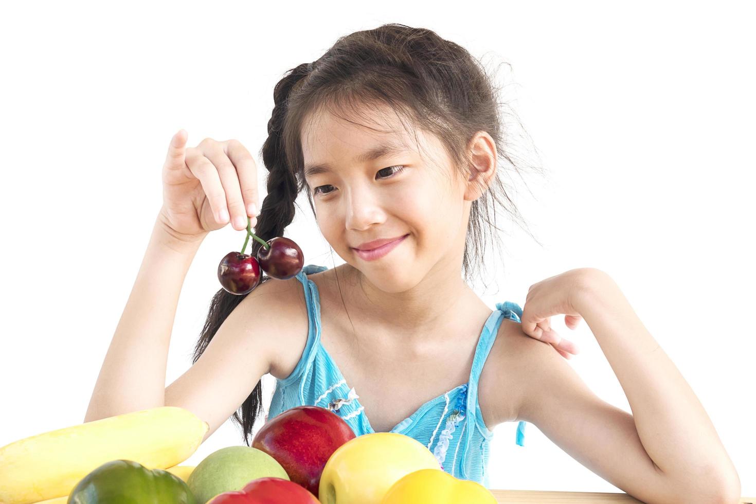 ragazza asiatica in buona salute che mostra felice espressione con varietà di frutta e verdura colorate isolate su sfondo bianco foto