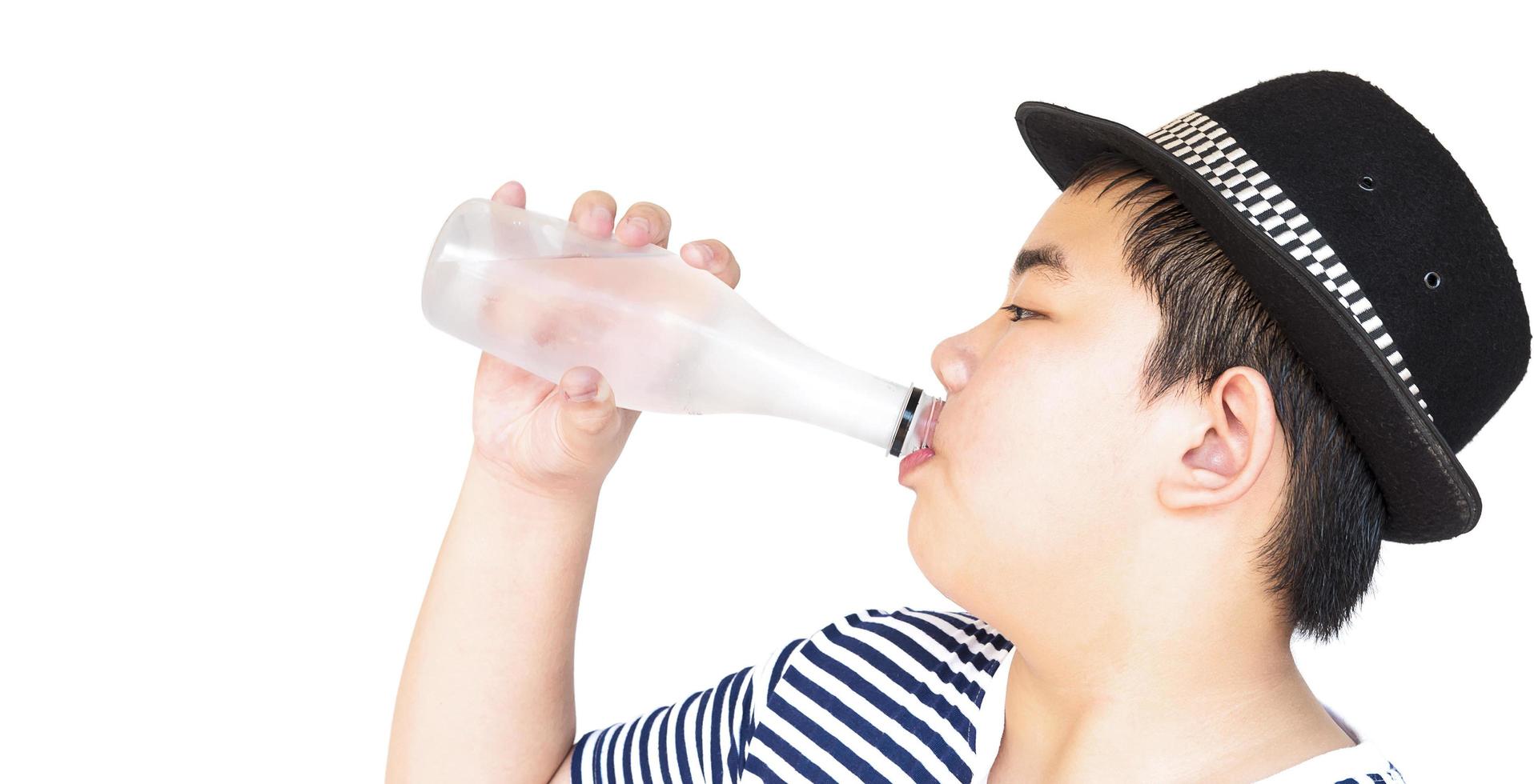 Il ragazzo di 14 anni sta bevendo una bottiglia di acqua fresca e fredda isolata sopra bianco foto