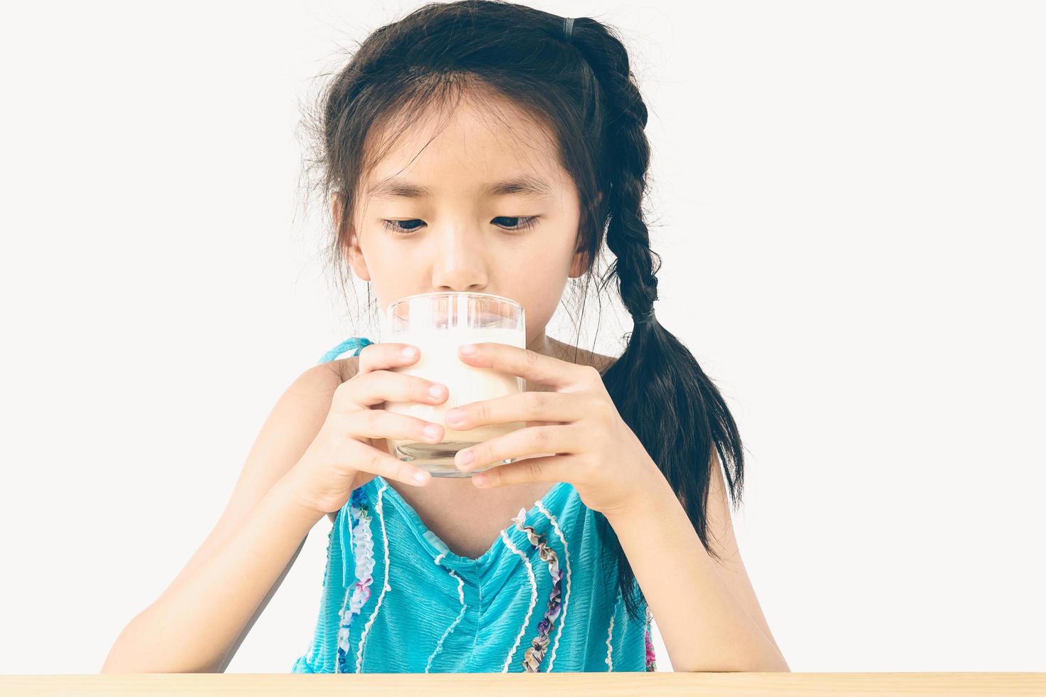 foto in stile vintage di una ragazza asiatica sta bevendo un bicchiere di latte su sfondo bianco